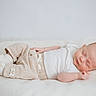 baby, sleeping, infant, blanket, white_clothing, beige_pants, knitted_booties, soft_texture, peaceful, resting, indoor, portrait, cute, newborn, child, calm, cozy, minimalist, relaxation, lying_down