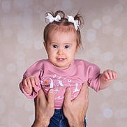 Madalynn is registered to the contest to win money with this photo: baby, child, girl, pink_shirt, white_bows, hands, portrait, cute, infant, smiling, studio, bokeh, background, holding, human, person, face, young, happy, casual