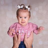 baby, child, girl, pink_shirt, white_bows, hands, portrait, cute, infant, smiling, studio, bokeh, background, holding, human, person, face, young, happy, casual