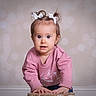 toddler, child, pink_sweatshirt, pigtails, white_bows, indoor, portrait, cute, curious, face, hands, stool, young_child, baby, expression, candid, light_background, small_person, clothing, person