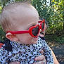 adult_hand, baby, casual, child, cute, face, fashion, greenery, hair, heart_shaped, holding, joy, leopard_print, nature, outdoor, people, red_sunglasses, smile, sunglasses, sunlight