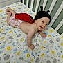 Hope is registered to the contest to win money with this photo: baby, infant, crawling, crib, bed, hat, knitted_hat, ladybug_costume, red_wings, smiling, happy, child, indoors, sheet, patterned_sheet, moon, sun, stars, clouds, cute