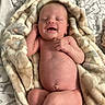 newborn, baby, smiling, blanket, patterned_blanket, sleeping, cozy, skin, infant, bedspread, floral_pattern, soft_texture, lying_down, happy, cute, small, human, indoors, relaxing, peaceful