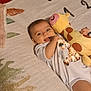 Zahara is registered to the contest to win money with this photo: baby, infant, smiling, plush_toy, giraffe, blanket, lying_down, cute, child, happy, indoors, person, soft_toy, clothing, face, head, hand, toy, comfort, playful