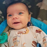 Zahara is registered to the contest to win money with this photo: baby, smiling, blue_blanket, onesie, milk_carton_pattern, cookie_pattern, infant, face, eyes, happy, lying_down, soft_texture, cozy, cute, child, indoor, portrait, blanket, newborn, warm