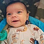 baby, smiling, blue_blanket, onesie, milk_carton_pattern, cookie_pattern, infant, face, eyes, happy, lying_down, soft_texture, cozy, cute, child, indoor, portrait, blanket, newborn, warm
