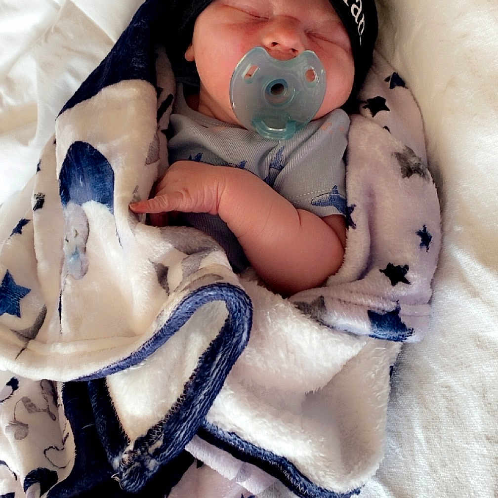 Coy is registered to the contest to win money with this photo: baby, bed, blanket, child, clothing, cozy, cute, face, hand, hat, indoors, infant, newborn, nursery, pacifier, resting, sleeping, soft, star_pattern, wrapped