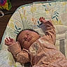 baby, sleeping, infant, baby_seat, pink_clothing, arms_up, indoor, peaceful, cute, young_child, floral_pattern, fabric, comfort, resting, child, small_hands, head, closed_eyes, toy, humor