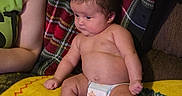 Tinsley is registered to the contest to win money with this photo: baby, infant, diaper, blanket, colorful, towel, sunflower, person, arm, skin, sitting, indoors, cute, plaid, fabric, couch, relaxed, child, young, casual