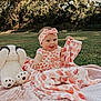 baby, blanket, child, cute, dog_toy, floral_clothing, grass, happy, headband, heart_pattern, nature, outdoor, pink, playful, plush_toy, portrait, sitting, smiling, sunlight, toy