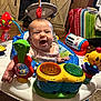 Ivory joined the competition — help win amazing prizes! baby, smiling, toy, activity_center, colorful, indoor, child, happy, face, furniture, living_room, wooden_floor, drum, guitar_toy, yellow_toy, blanket, carpet, person, infant, seat