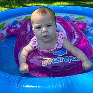 Ivory is registered to the contest to win money with this photo: baby, inflatable_ring, pool, water, outdoor, summer, child, swimming, float, grass, tree, sunlight, pink_clothing, expression, backyard, recreation, play, person, daylight, inflatable_pool