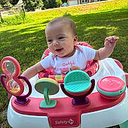 Ivory is registered to the contest to win money with this photo: baby, walker, outdoor, grass, smiling, child, toy, onesie, sunlight, greenery, happy, infant, playtime, suburban, daylight, person, cute, colorful, nature, portrait