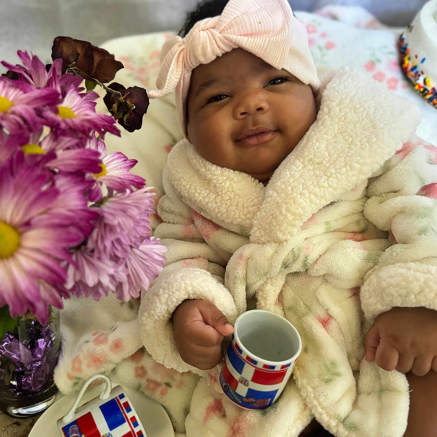 Jameline joined the competition — help win amazing prizes! baby, bow, cake, celebration, child, cute, decor, flowers, happy, headband, indoor, infant, mug, portrait, purple_flowers, robe, smiling, soft_texture, table, warm_clothing