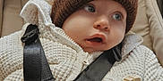 Lío a rejoint le concours — aidez-le/la à gagner de superbes lots ! baby, brown_hat, child, closeup, comfortable, curious, cute, expression, face, indoors, infant, person, pom_pom, safety_harness, seatbelt, soft_lighting, stroller, warm_clothing, white_jacket, zipper