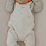 baby, infant, pacifier, clothing, overalls, sneakers, lying_down, soft_texture, beige, gray, cute, child, small_hands, footwear, portrait, indoor, calm, curious, newborn, casual