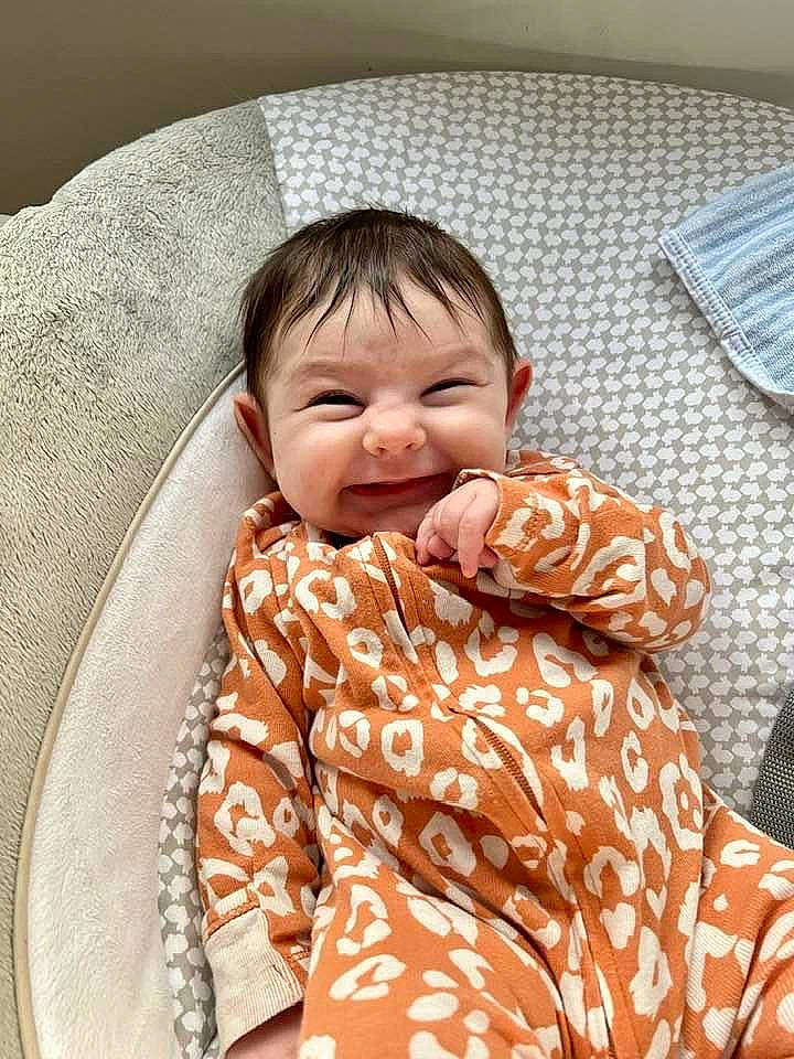 Juliana is registered to the contest to win money with this photo: baby, baby_toddler_clothing, bedding, cheek, child, circle, collar, comfort, eye, fun, happy, laugh, linens, pattern, person, sitting, skin, sleeve, smile, textile