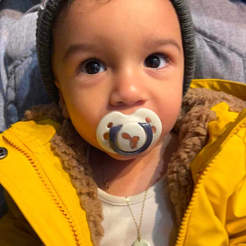 Erik joined the competition — help win amazing prizes! accessories, baby, biting, cap, clothing, coat, eating, face, food, hat, head, jacket, jewelry, necklace, person, sitting