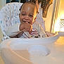 Kay'Cee joined the competition — help win amazing prizes! toddler, child, high_chair, smiling, indoor, clothing, lamp, furniture, baby, seat, person, face, happy, curly_hair, hand, table, room, light, expression, home