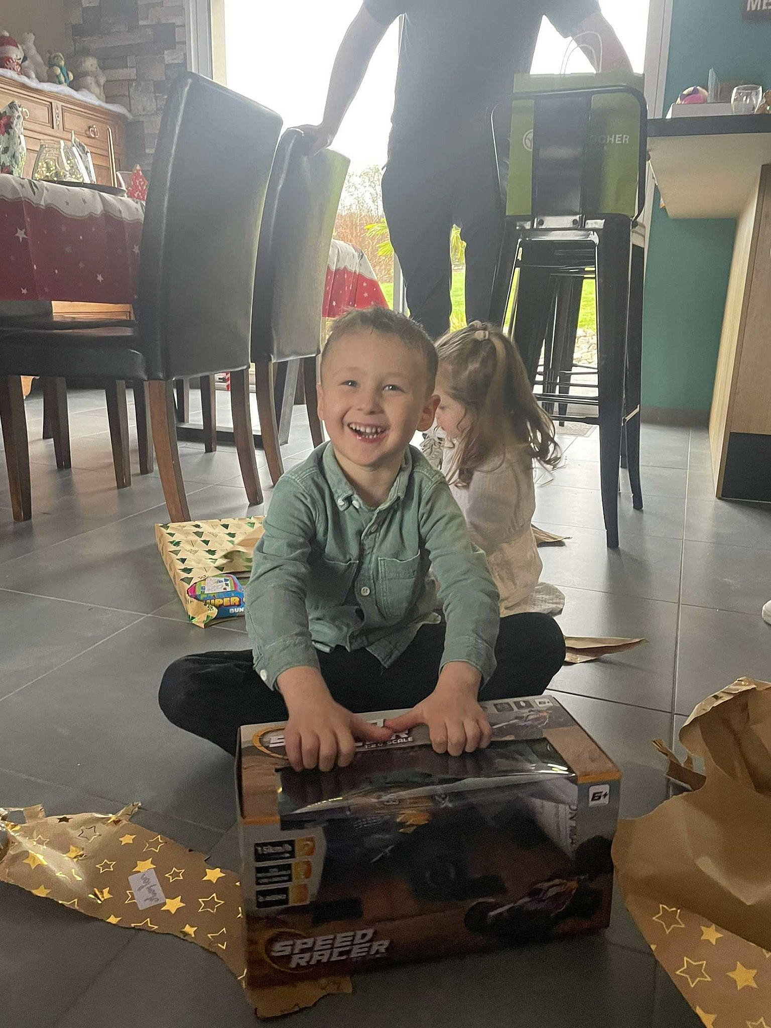 Maylon a rejoint le concours — aidez-le/la à gagner de superbes lots ! bag, box, chair, child, coffee_table, event, flooring, fun, joy, leisure, luggage_and_bags, person, recreation, room, shipping_box, sitting, smile, t_shirt, table, television