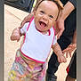 Naziyah is registered to the contest to win money with this photo: baby, child, smiling, headband, bow, bib, colorful_pants, white_shoes, outdoor, concrete, adult_hands, supporting, car_door, happy, walking, toddler, footwear, person, closeup, daylight