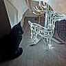 Chanel a rejoint le concours — aidez-le/la à gagner de superbes lots ! black_cat, cat, animal, pet, indoor, wooden_floor, reindeer_decoration, holiday_lights, fairy_lights, wireframe, festive, curious, decoration, dark, shadow, flooring, cozy, glowing, night, home