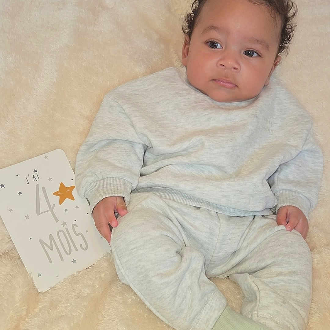 Sehyan participe au concours pour gagner de l'argent avec cette photo : baby, celebration, child, cozy, curly_hair, cute, face, gray_clothing, hand, indoors, infant, milestone, milestone_card, portrait, resting, sitting, skin, socks, soft_blanket, young_child