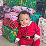 Sehyan participe au concours pour gagner de l'argent avec cette photo : baby, child, santa_claus_costume, christmas, presents, gift_wrap, holiday, festive, smiling, indoors, floor, red_clothing, black_boots, cute, seasonal, celebration, portrait, happy, wrapped_gifts, dinosaur_pattern