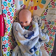 Brian is registered to the contest to win money with this photo: baby, blanket, dinosaur_pattern, baby_rocker, colorful, lion_face, infant, cozy, wrapped, cute, child, indoor, soft_fabric, patterned_fabric, small_face, lying_down, comfort, toy, seat, young_child