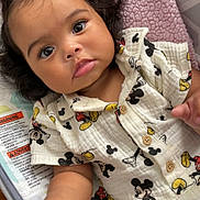 Leilani joined the competition — help win amazing prizes! baby, infant, child, mickey_mouse, shirt, clothing, blanket, baby_seat, soft_texture, curly_hair, cute, hand, face, eyes, indoor, comfort, portrait, expression, young_child, baby_girl