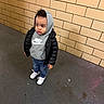 Tyler is registered to the contest to win money with this photo: black_jacket, casual_clothing, child, concrete_floor, curly_hair, expression, floor, hoodie, indoor, jeans, looking_away, nike, person, standing, tiles, toddler, urban, wall, white_sneakers, young