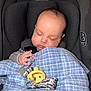 baby, infant, sleeping, car_seat, blanket, pacifier, hand, face, head, harness, safety_label, newborn, plaid_blanket, blue_blanket, gray_seat, closeup, indoor, soft_lighting, peaceful, binky