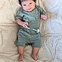 baby, child, infant, smile, happy, green_outfit, shorts, tshirt, dark_hair, barefoot, blanket, soft_texture, lying_down, cute, portrait, indoors, cozy, small_hands, small_feet, comfortable
