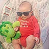 Myles joined the competition — help win amazing prizes! baby, baby_chair, bouncer, child, cute, dinosaur_toy, fashionable, indoors, infant, leaf_pattern, patterned_fabric, photography, plush_toy, portrait, red_outfit, relaxed, seated, sunglasses, toes, toy