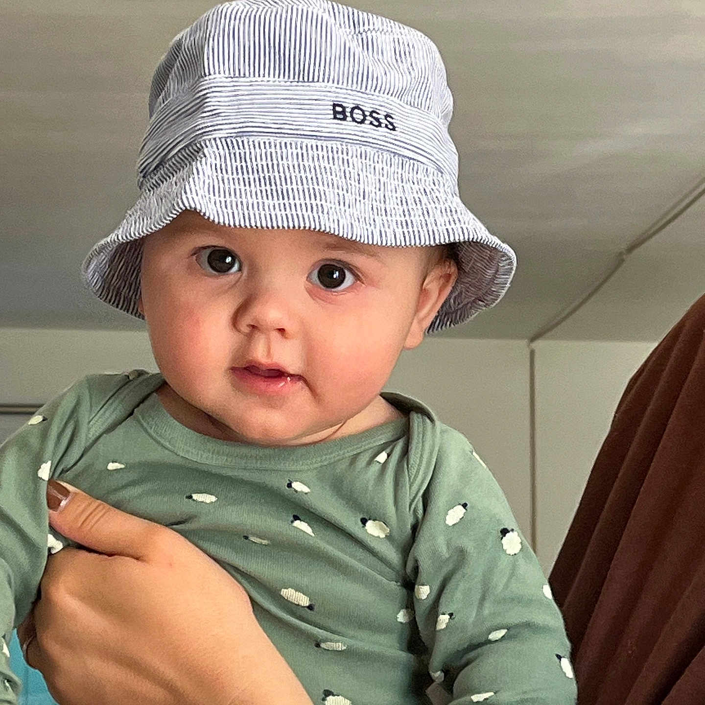 Léandre participe au concours pour gagner de l'argent avec cette photo : baby, child, hat, bucket_hat, green_clothing, polka_dots, hand, indoor, person, cute, portrait, face, eyes, skin, nails, apparel, headwear, expression, holding, fashion
