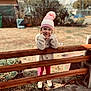 beanie, cap, child, clothing, coat, face, female, girl, grass, happy, hat, head, pants, person, photography, plant, portrait, smile, soil, wood
