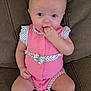 Phoebe is registered to the contest to win money with this photo: baby, infant, child, pink_onesie, polka_dot, couch, furniture, sitting, hand_in_mouth, cute, portrait, skin, face, eyes, chubby_legs, indoors, comfortable, expression, young, person