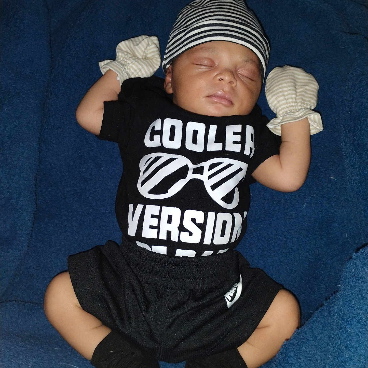 Kassiah is registered to the contest to win money with this photo: baby, sleeping, black_clothing, striped_hat, mittens, blue_blanket, infant, cute, newborn, soft_texture, resting, child, portrait, indoors, cozy, small, hands_up, socks, peaceful, person