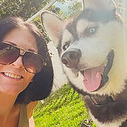 Lux is registered to the contest to win money with this photo: woman, dog, siberian_husky, smiling, sunglasses, outdoor, grass, sunlight, pet, happy, tongue_out, leash, nature, summer, portrait, face, canine, daylight, trees, fun