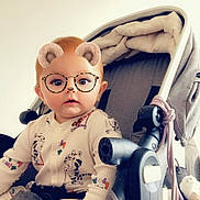 Rose participe au concours pour gagner de l'argent avec cette photo : baby, child, stroller, onesie, patterned_clothing, face_filter, bear_ears, glasses_filter, indoor, infant, cute, seated, hand, expression, light_background, soft_lighting, toy, blanket, person, portrait