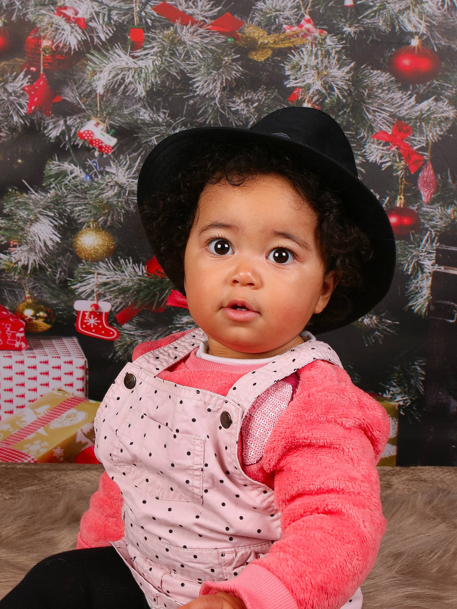 Thaïs a rejoint le concours — aidez-le/la à gagner de superbes lots ! baby_toddler_clothing, black_hair, cap, cheek, christmas_tree, costume_hat, facial_expression, fun, happy, headgear, lip, outerwear, pattern, person, pink, red, skin, sleeve, standing, sun_hat