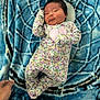 Amelia joined the competition — help win amazing prizes! baby, infant, floral_onesie, blanket, blue_blanket, plush, hand, face, person, newborn, lying_down, cute, pattern, soft_texture, indoor, portrait, sleepwear, comfort, small_hand, cozy