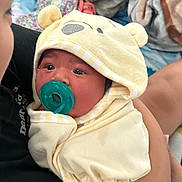 Amelia is registered to the contest to win money with this photo: baby, pacifier, blanket, hood, yellow, clothing, child, infant, face, person, holding, soft, cute, sleepwear, cozy, comfort, indoor, human, newborn, toddler