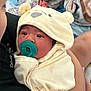 baby, pacifier, blanket, hood, yellow, clothing, child, infant, face, person, holding, soft, cute, sleepwear, cozy, comfort, indoor, human, newborn, toddler