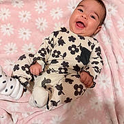 Ella is registered to the contest to win money with this photo: baby, black_and_white, blanket, child, cozy, cute, floral_clothing, happy, indoors, infant, lying_down, pink, playful, portrait, small_hands, smiling, socks, soft_texture, white_flowers, young