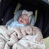 Octavia is registered to the contest to win money with this photo: baby, smiling, blanket, car_seat, headband, infant, cozy, cute, child, portrait, outdoor, clothing, face, person, soft, happy, bundle, seat, warm, small