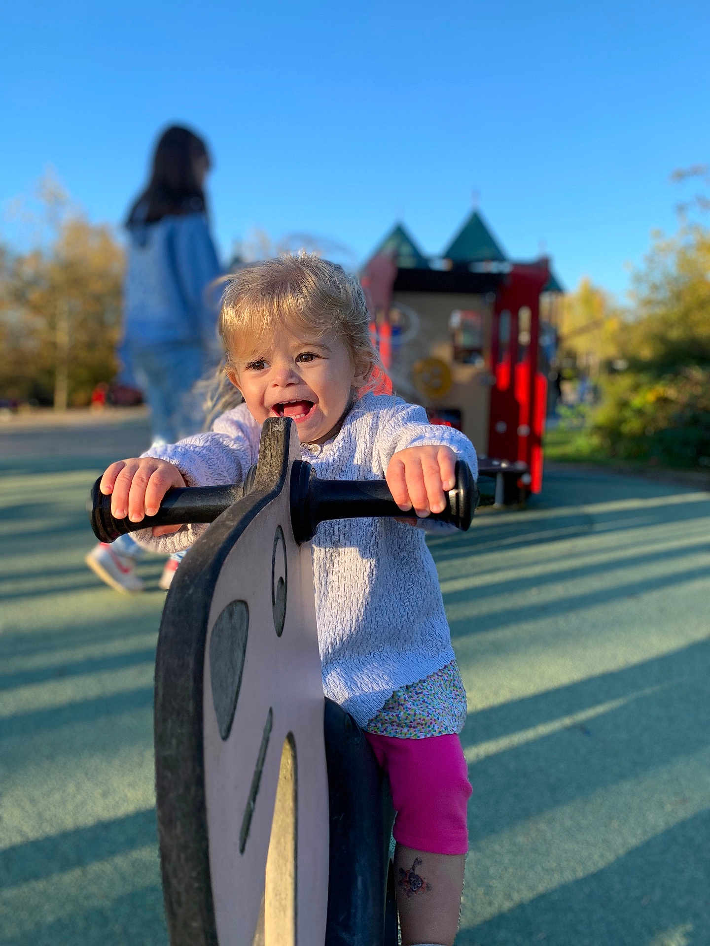 Maïween a rejoint le concours — aidez-le/la à gagner de superbes lots ! toddler, child, playground, play_equipment, ride, happy, smiling, outdoor, daylight, blue_sky, person, toy, fun, girl, handlebar, casual_clothing, shadow, park, play, cute