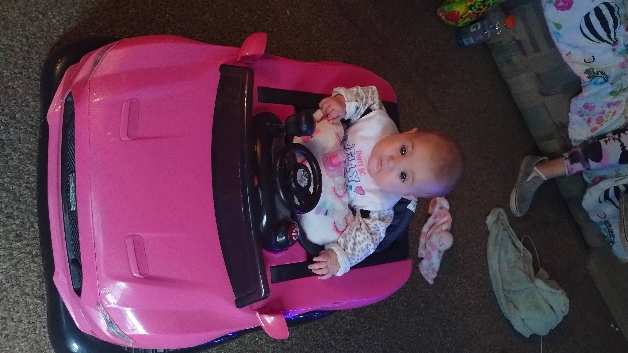 Cora is registered to the contest to win money with this photo: automotive_lighting, baby, baby_carriage, baby_products, baby_toddler_clothing, bumper, car, child, fender, fun, hood, magenta, person, pink, product, sitting, toddler, trunk, vehicle, vehicle_door