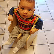 Léo participe au concours pour gagner de l'argent avec cette photo : baby, child, toddler, chair, colorful_clothing, patterned_shirt, gray_pants, white_socks, tiled_floor, indoor, cute, looking_up, wooden_chair, seated, small_hands, curious, floor_tiles, young_child, casual_wear, infant