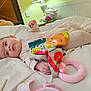 Eliora is registered to the contest to win money with this photo: baby, infant, bed, blanket, toy, stuffed_animal, clothing, hand, face, head, pillow, room, indoor, radiator, lamp, table, colorful, cute, child, sleepwear